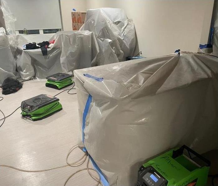 An Albany hotel room with plastic on the furniture and our SERVPRO drying equipment.