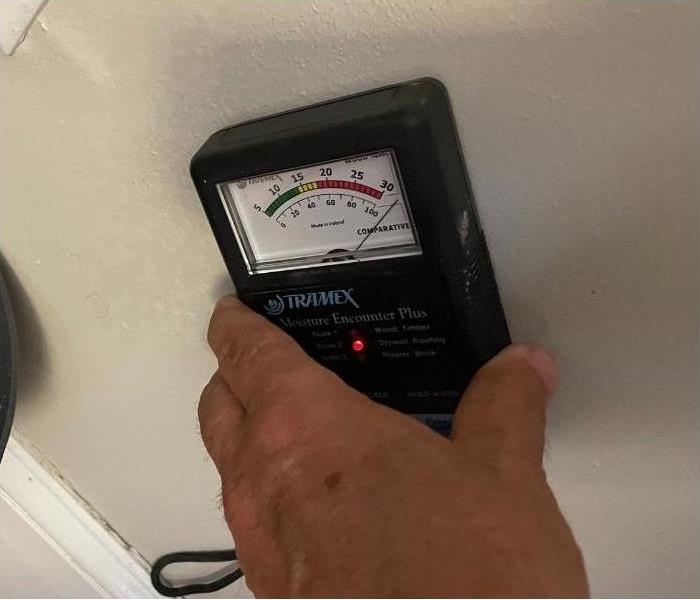 Our SERVPRO professional holding a moisture meter up to a wall to determine the water in the walls.