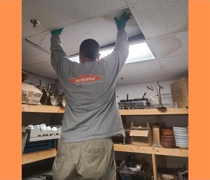 A SERVPRO technician working on water damage in the ceiling of an Albany business.