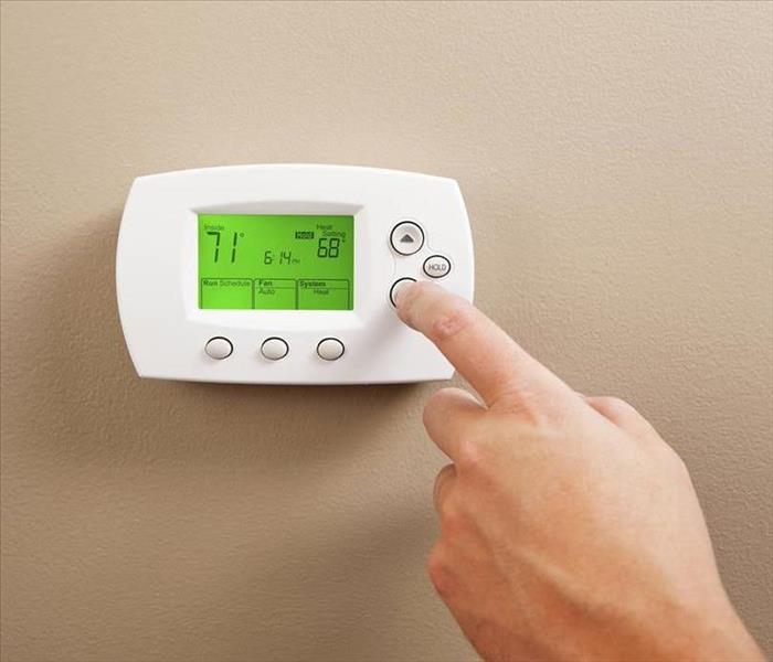 A hand changing the temperature on the thermostat.